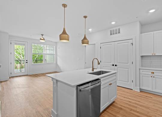 A kitchen with white cabinets and a wooden floor.