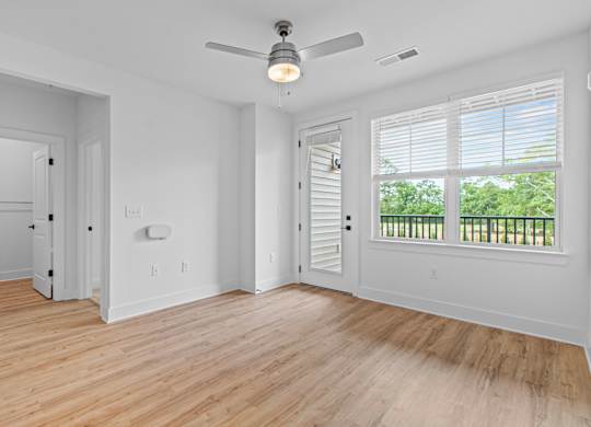 A room with a ceiling fan and wooden flooring.