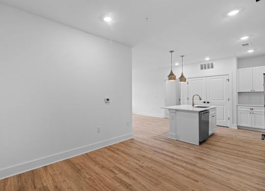 A kitchen with white cabinets and a wooden floor.
