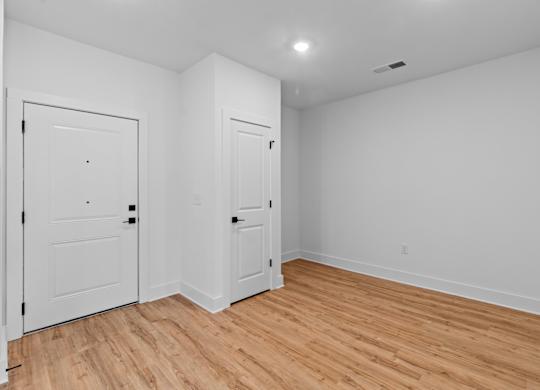 A room with two doors and a wooden floor.