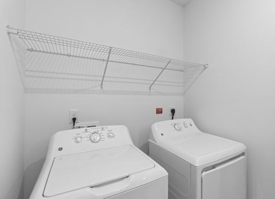 Two white front loading washing machines in a laundry room.