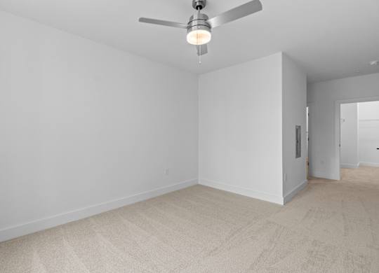 A room with a ceiling fan and carpeted floor.