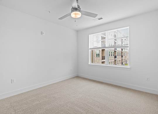 A room with a ceiling fan and a window with blinds.