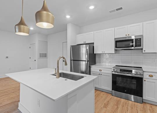 A modern kitchen with a white countertop and stainless steel appliances.
