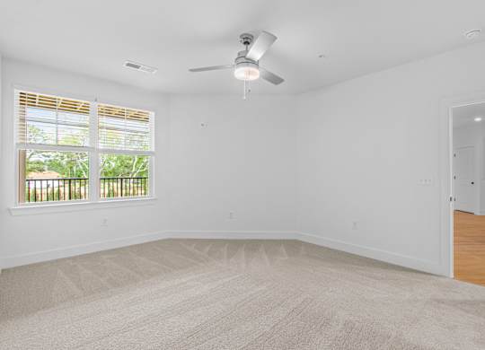 A room with a ceiling fan and carpeted floor.
