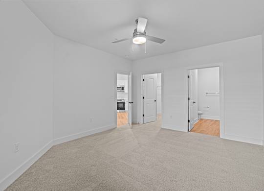 A room with a ceiling fan and carpeted floor.
