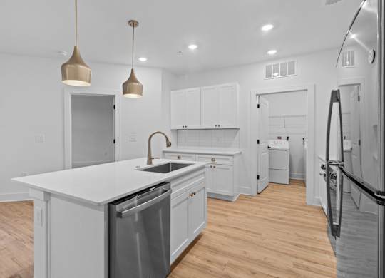 A kitchen with white cabinets and a wooden floor.