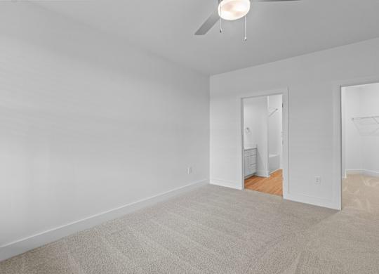 A room with a ceiling fan and carpeted floor.