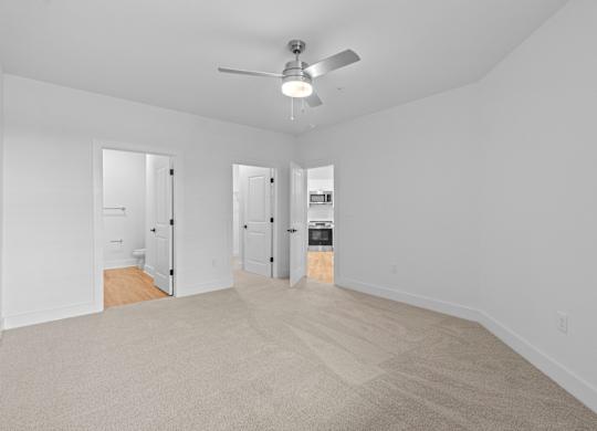 A room with a ceiling fan and carpeted floor.