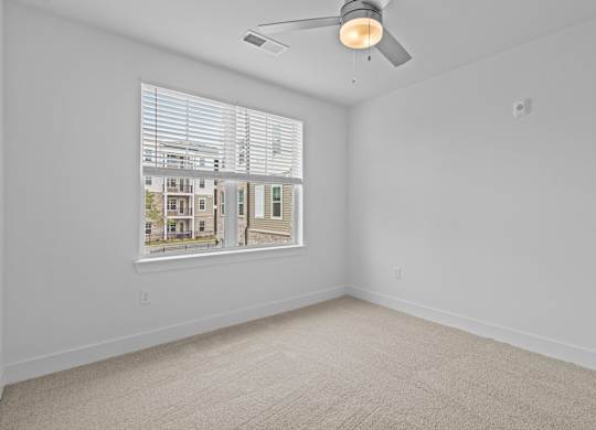 A room with a window showing a view of a building outside.