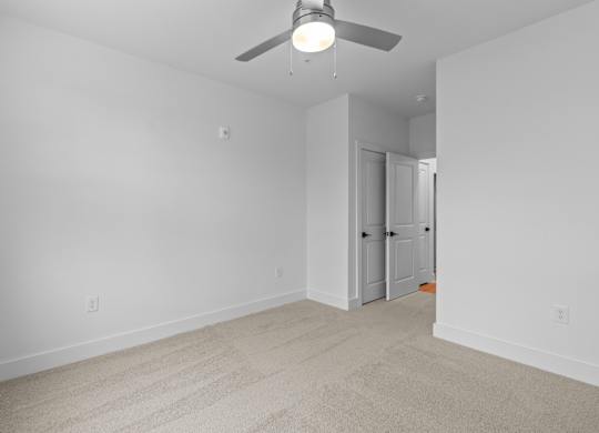 A room with a ceiling fan and carpeted floor.
