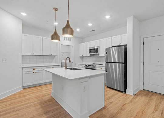 A kitchen with white cabinets and a white island.