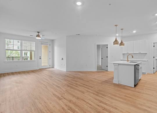 A spacious kitchen with wooden floors and white walls.