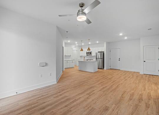 A spacious kitchen with a fan and wooden flooring.