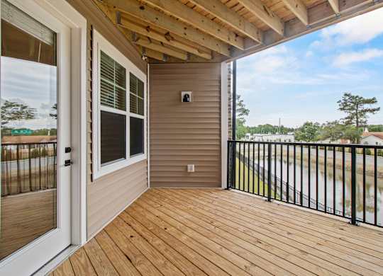 A wooden deck with a black railing and a sliding glass door.
