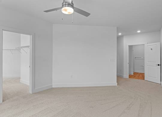 A room with a ceiling fan and carpeted floor.