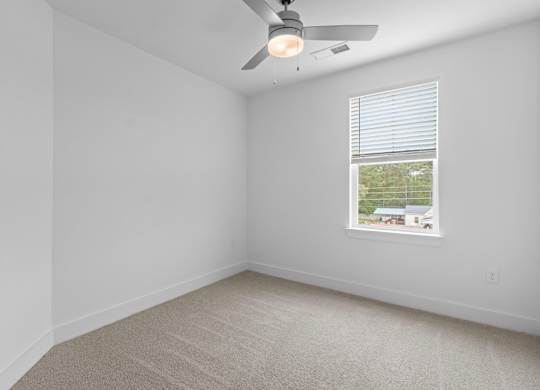 A room with a ceiling fan and a window with blinds.