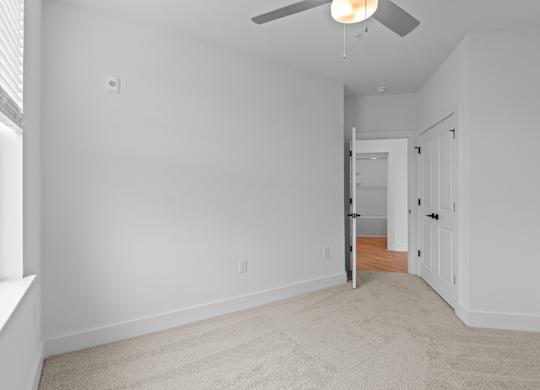 A room with a carpeted floor and a ceiling fan.