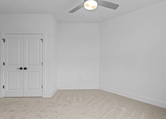 A white door is in a room with a ceiling fan.