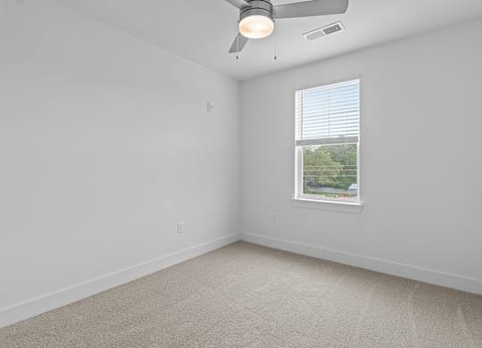 A room with a ceiling fan and a window with blinds.