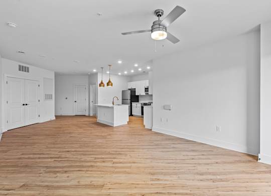 A spacious room with wooden floors and a ceiling fan.