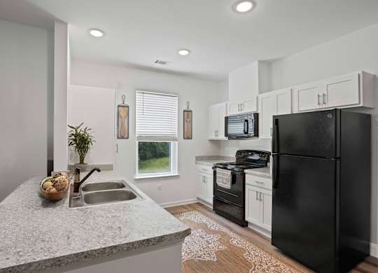 Ovata at Reedy Creek kitchen with modern appliances, a peninsula, white cabinetry and LVT flooring.
