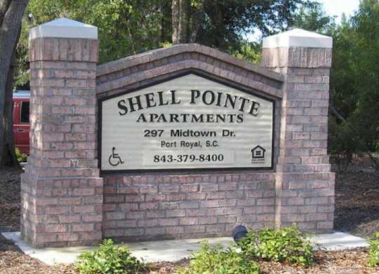 a sign for shell pointe apartments in front of a brick wall
