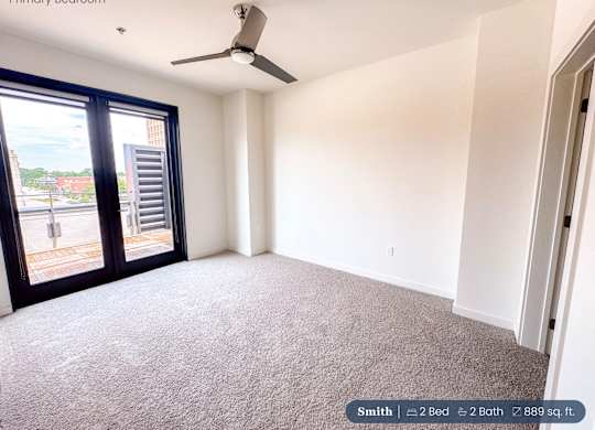 A bedroom with a carpeted floor and a ceiling fan.