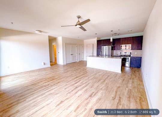 A spacious living room with a ceiling fan and hardwood floors.