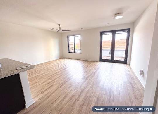 A spacious room with a ceiling fan and a large window.