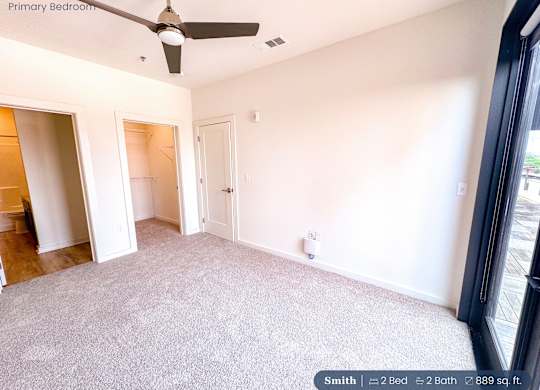 A bedroom with a ceiling fan and two bathrooms.