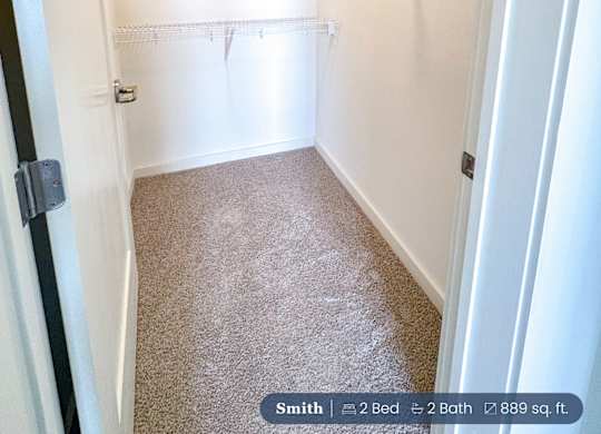A small bedroom closet with a carpeted floor and a white door.