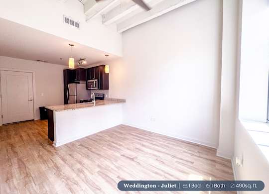 A spacious room with a kitchenette and a window.
