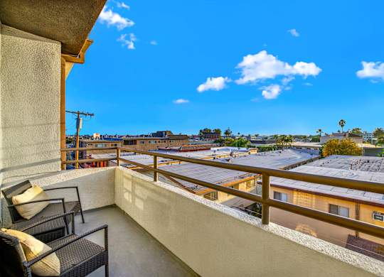 A balcony with a chair and a table overlooking a residential area at Twelve One Ten Rochester, Los Angeles, 90025