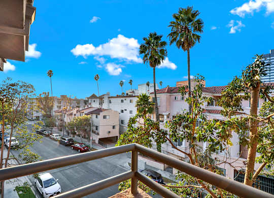 A balcony view of a residential area with palm trees at Twelve One Ten Rochester, Los Angeles