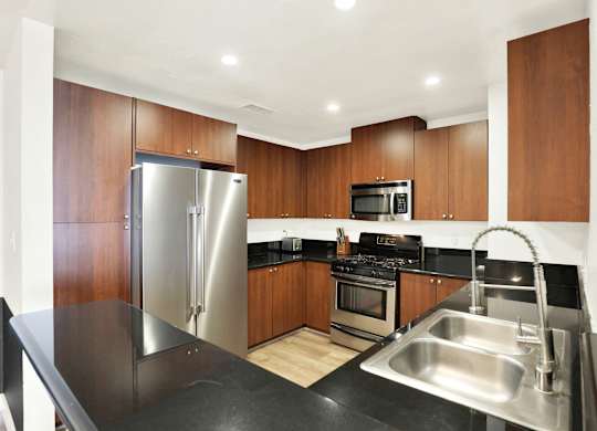 A modern kitchen with a stainless steel sink and refrigerator at Twelve One Ten Rochester, Los Angeles, CA 90025