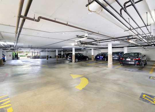 A parking garage with several cars parked and a yellow arrow on the ground at Twelve One Ten Rochester, Los Angeles