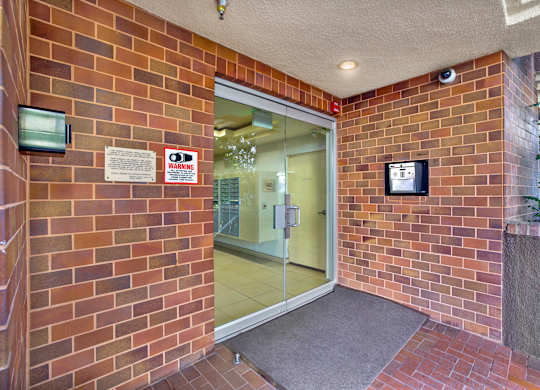 A red brick wall with a glass door and a warning sign at Peach Tree Court, Los Angeles, CA