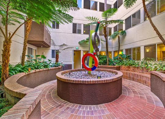 A circular brick patio with a fountain in the middle at Peach Tree Court, Los Angeles, CA