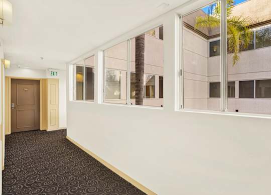 A hallway with a carpeted floor, white walls, and a door on the left at Peach Tree Court, California 90024
