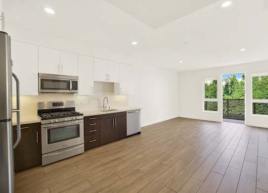 A kitchen with wooden floors and stainless steel appliances at The Urbanpolitan, Los Angeles
