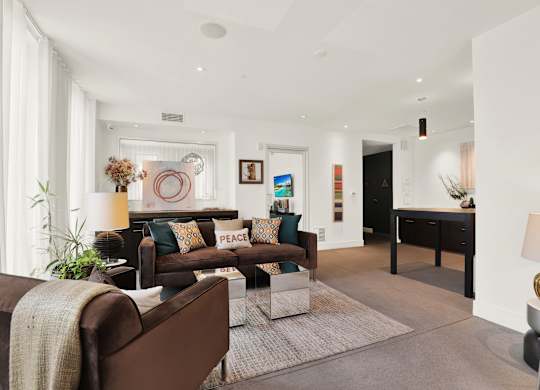 A living room with a brown couch and a white rug at The Urbanpolitan, Los Angeles, 90036