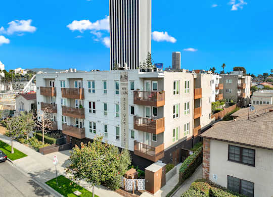 A tall building with a white facade stands in front of a row of houses at The Urbanpolitan, Los Angeles, California