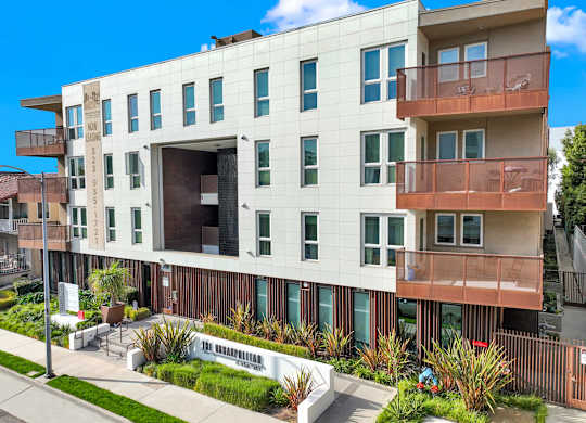 A modern apartment building with a white facade and balconies at The Urbanpolitan, Los Angeles, California