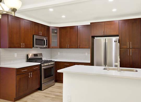 A kitchen with brown cabinets and a white counter at Wooster Encore Apartments, Los Angeles, CA 90035