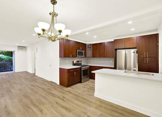 A modern kitchen with wooden cabinets and a white island at Wooster Encore Apartments, Los Angeles