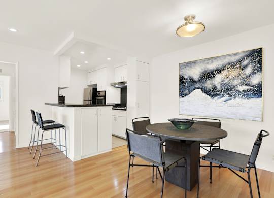 A modern kitchen with a dining table and chairs at Wooster Encore Apartments, Los Angeles, CA