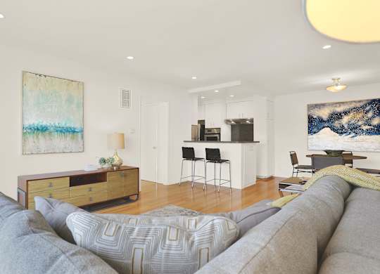 A living room with a grey couch and a painting on the wall at Wooster Encore Apartments, California 90035