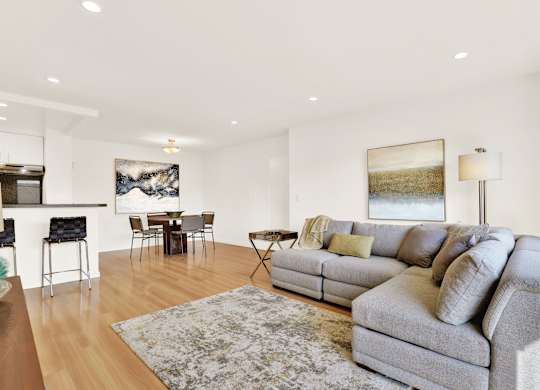 A living room with a grey couch and a rug at Wooster Encore Apartments, Los Angeles, CA 90035