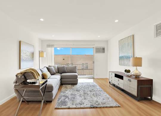 A modern living room with a grey sofa and a wooden floor at Wooster Encore Apartments, California